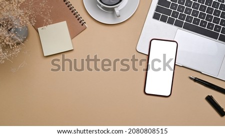 Top view smart phone, laptop computer and notebook on beige background.