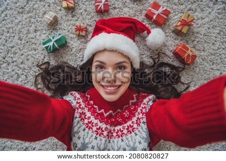 Top view photo portrait smiling woman wearing headwear laying on floor in xmas clothes taking selfie