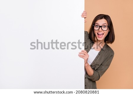Photo of funny promoter lady hold white wall blackboard wear specs khaki shirt isolated beige color background Royalty-Free Stock Photo #2080820881