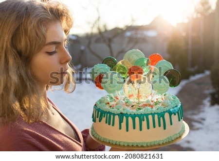 cute dreamy beautiful birthday girl holding a big beautiful cake with lollipops and marshmallows on sticks. Holiday, congratulations, happiness, joy, pleasure, dreams. copy space