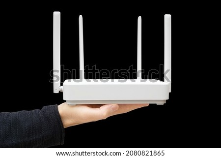 Male hand holding a modern dual band router against a black background. Upgrading to wi-fi 6.