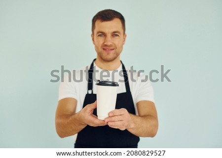 Man in uniform standing in the studio with drink in hands.