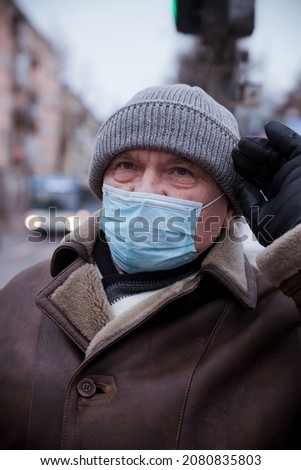 Elderly  man in protective medical mask  on   street.