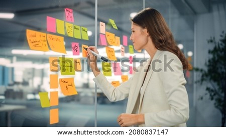 Young Confident Businesswoman Creating Project Plan on Office Wall with Paper Notes. Stylish Beautiful Manager Working on Business, Financial and Marketing Projects. Specialist in Diverse Team. Royalty-Free Stock Photo #2080837147