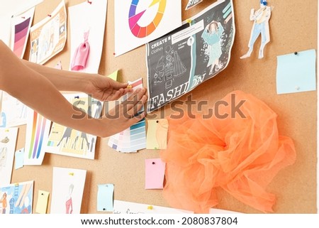 Fashion designer attaching pictures to board in studio