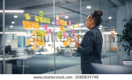 African American Businesswoman Creating Project Plan on Office Wall with Paper Notes. Stylish Confident Manager Working on Business, Financial and Marketing Projects. Specialist in Diverse Team. Royalty-Free Stock Photo #2080839748