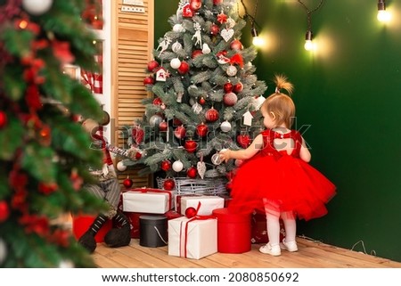 little girl playing with toys near the Christmas tree