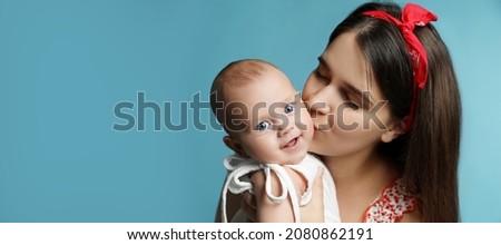 Beautiful mother kissing her cute baby on light blue background, space for text. Banner design 