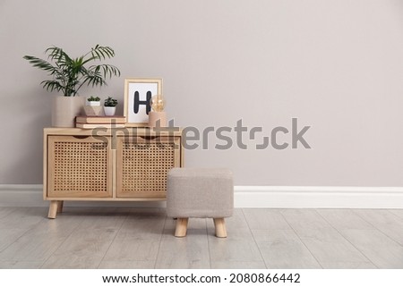 Stylish pouf and cabinet near beige wall indoors. Space for text Royalty-Free Stock Photo #2080866442