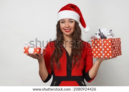 Young woman in red santa claus hat holding present box. Beautiful woman with christmas gifts box on white background with copy space