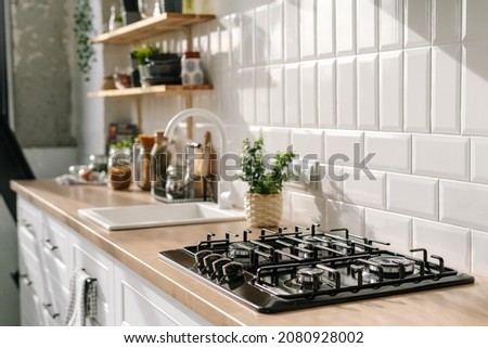 Side view of scandinavian style kitchen interior in white tones with stove, sink and shelves. Luxury apartment for sale. Cozy place for cooking concept Royalty-Free Stock Photo #2080928002