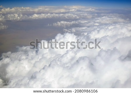 View of fluffy clouds from plane. Blue sky on horizon. Copy space. Close-up. Selective focus.