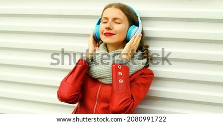 Portrait of happy smiling young woman listening to music in headphones on white background