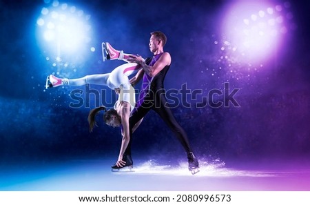 Duo figure skating in action on dark blue background