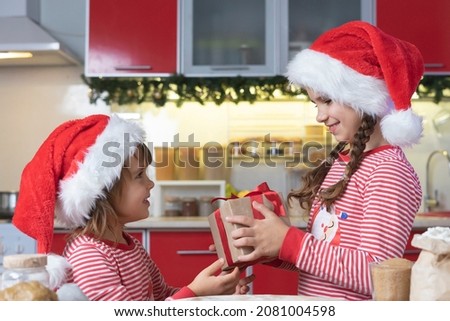 Happy family gives Christmas gifts at home in the kitchen. Merry Christmas at home with your family in Santa hats. Winter Holiday. 