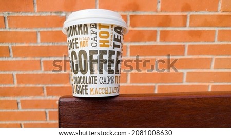 cardboard cup of coffee to go on a bench table with the name of different types of coffee in different languages