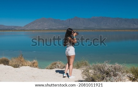 Girl explorer photographing the "Playitas" lagoon in Cuatrociénegas, Coahuila, Mexico. Dressed in white shorts for the desert heat, she takes pictures and enjoys the oasis landscape 
