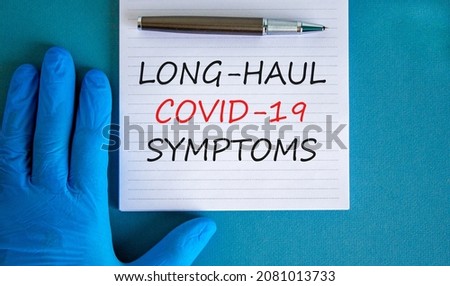 COVID-19 long-haul covid symptoms symbol. White card with words Long-haul covid-19 symptoms. Doctor hand, pen, blue background, copy space. Medical, COVID-19 long-haul covid symptoms concept.