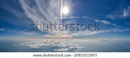 Aerial view from airplane window at high altitude of earth covered with white thin layer of misty haze and distant clouds. Royalty-Free Stock Photo #2081021893