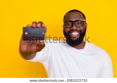 Photo of blurred positive guy arm hold plastic debit card beaming smile isolated on yellow color background