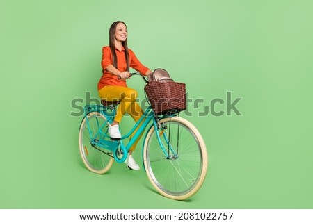Full length profile side photo of young woman enjoy riding vehicle isolated over green color background