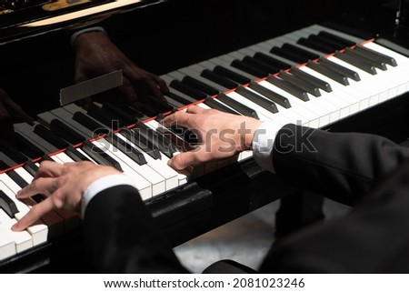 Photo of a professional pianist performing on a grand piano. Royalty-Free Stock Photo #2081023246