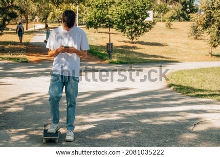 teenage boy with mobile phone and skateboard on the street