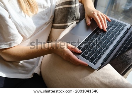 Girl works on the laptop on the couch at home or in hotels. Remote work. Office at home. Woman in the bedroom is typing on a laptop, distance learning for students, surfing the Internet