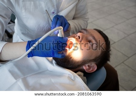 Dentist make ultrasonic teeth cleaning close-up. Removal of tartar and plaque. prevention of dental disease paradontitis and paradantoz.  Royalty-Free Stock Photo #2081063590