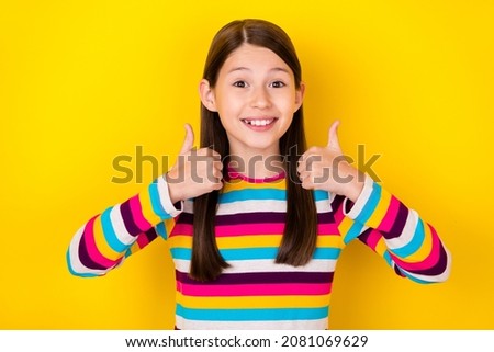 Photo of positive little lady raise thumbs up give positive feedback wear striped shirt isolated yellow color background