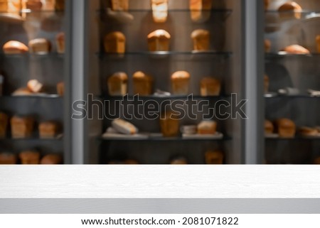White wooden table with blurry background of bakery shop.