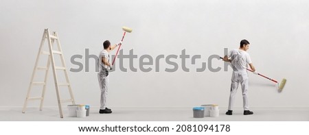 Rear view shot of house painters painting a wall isolated on white background Royalty-Free Stock Photo #2081094178