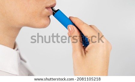 Caucasian woman smokes disposable vape on white background. Alternative device for smoking.