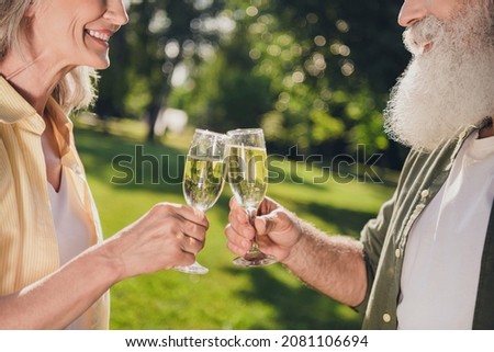Photo of positive good mood pensioner friends dressed casual shirts smiling drinking champagne walking outdoors urban city park