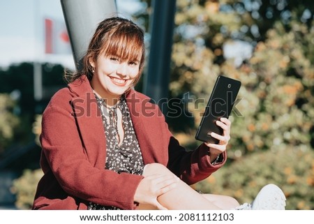 Young redhead business woman smiling to camera while using the tablet out of the office. Copy space image, business and work at the office concept. Outside the office, elegant trendy look