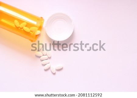 Oval pills and orange pill bottles were spread out on the white tabletop.