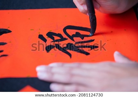 asian people write calligraphy on couplet to celebrate chinese new year with word meaning luck Royalty-Free Stock Photo #2081124730