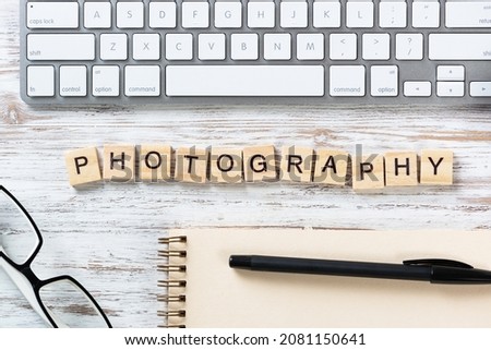 Photo studio advertising with letters on cubes. Still life of workplace with supplies. Flat lay vintage wooden desk with computer keyboard and spiral notebook. Create photography and visual content