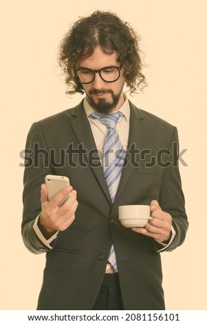 Studio shot of handsome bearded businessman with curly hair in suit isolated against white background