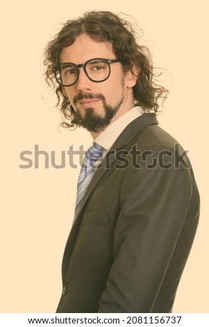 Studio shot of handsome bearded businessman with curly hair in suit isolated against white background