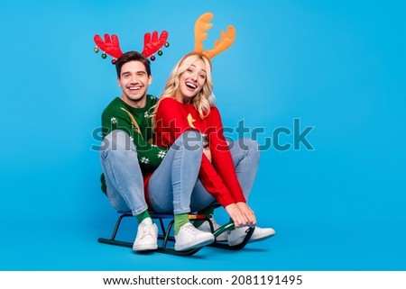 Photo of charming cute young couple dressed ugly print sweaters smiling sledding isolated blue color background