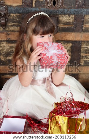 Little girl wearing a christmas dress looking at gifts