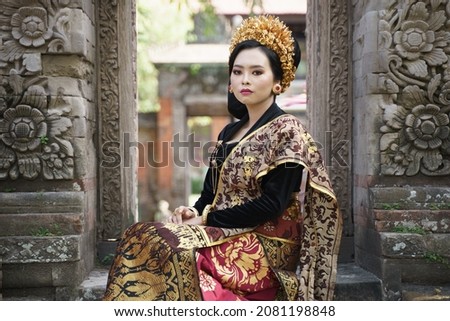 Women wear traditional Balinese kebaya between the relief gates Royalty-Free Stock Photo #2081198848