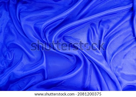 The texture of the flowing satin fabric in blue. free space for your text. Canvas texture or background.