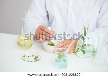 Plants and flowers extract in petri dish and a white background in laboratory , green leaf  in a test tube and doctor for cosmetic advertising , photography science concept
