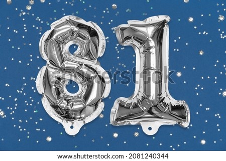 Silver foil balloon number, digit eighty one on a blue background with sequins. Birthday greeting card with inscription 81. Top view. Numerical digit. Celebration event, template.