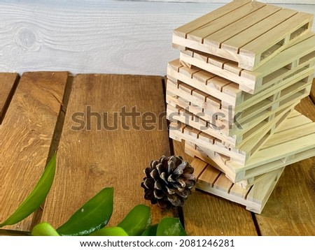 A zamiokulkas twig, a pine cone and wooden pallets lie on an oak table in the background, pine hay painted white