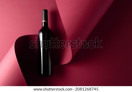 Bottle of red wine on a red background. Copy space for your text, top view.