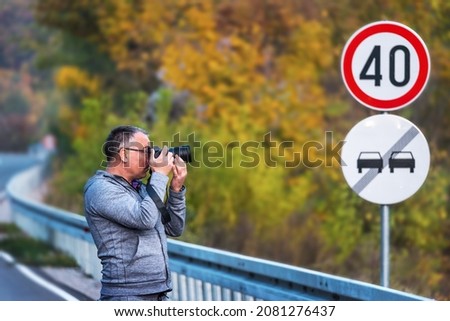 Photographer walks down a road in the autumn with his camera, taking photos. Selective Focus