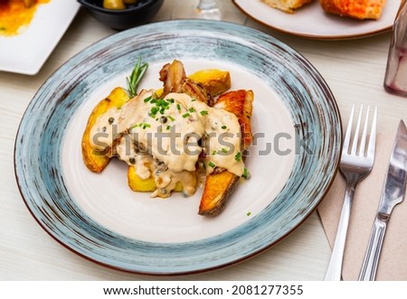 Delicious pork with Roquefort cheese sauce with baked potato slices with herds, decorated with a sprig of rosemary